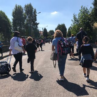 Genitori e bambini camminano in sicurezza sulle strade che portano a scuola. Effetto delle &quot;Zone scolastiche&quot;