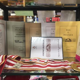 Una vetrina con le pubblicazioni e i simboli del Magistero dei Bruscitti nella cartoleria Tagliabue
