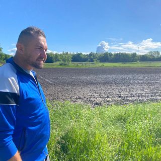 Fabio Pinton davanti alla campagna di Daverio sommersa dall'acqua e ora, con l'uscita del sole, invasa dal fango. Sotto nella gallery le foto dei terreni sommersi mercoledì scorso e l'indimenticabile papà Lino, da cui è nata l'azienda agricola, felice sul trattore