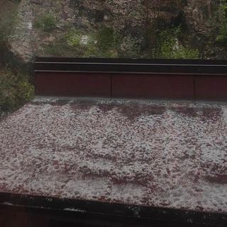 La grandine accumulata su una tettoia al Campo dei Fiori (foto da Olgher) e, sotto nella gallery, i chicchi raccolti da Ester a Melide (foto via NaturalMeteo) e il fiume bianco che ha invaso Verbania