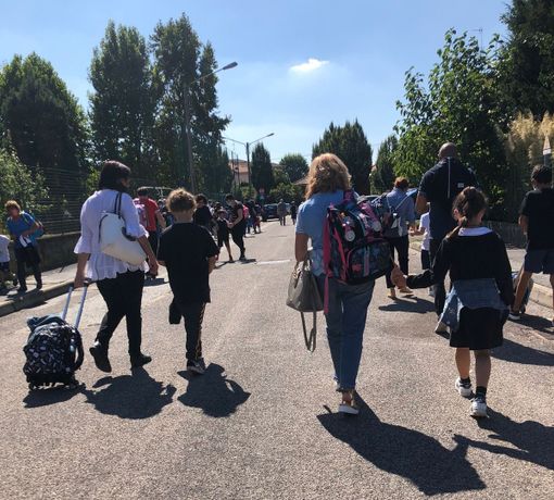 Genitori e bambini camminano in sicurezza sulle strade che portano a scuola. Effetto delle &quot;Zone scolastiche&quot;