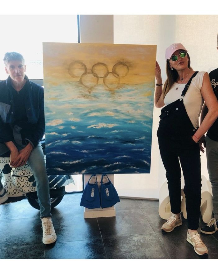 VIDEO E FOTO. Un mare increspato con i cinque cerchi olimpici: ecco il dipinto di Manuela Carnini con le pinne di Martinenghi