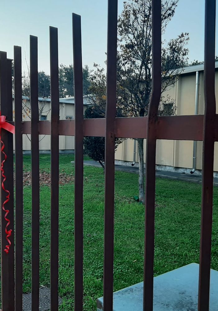 Fiocchi rossi sul cancello della scuola Toscanini di Legnano