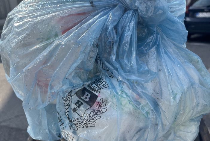 Un sacco azzurro in un cestino per strada