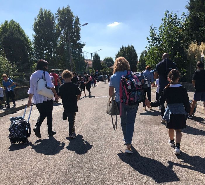Genitori e bambini camminano in sicurezza sulle strade che portano a scuola. Effetto delle "Zone scolastiche" Genitori e bambini camminano in sicurezza sulle strade che portano a scuola. Effetto delle "Zone scolastiche"