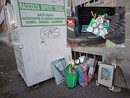 I rifiuti abbandonati per l'ennesima volta accanto al contenitore per materiale tessile in piazza XXV Aprile e, nel riquadro, il ritiro da parte di Luca, volontario di Casaringhio