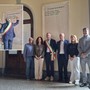Foto di gruppo alla scopertura del nome di Angelo Carenzi, nel riquadro il primo cittadino rimuove un residuo di protezione