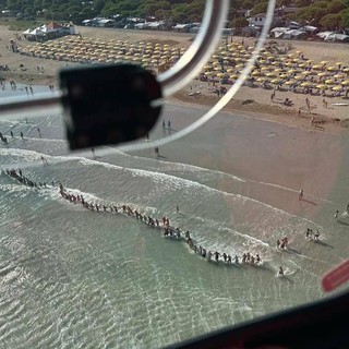 La catena umana dei bagnanti impegnati nelle ricerche del bambino a Jesolo